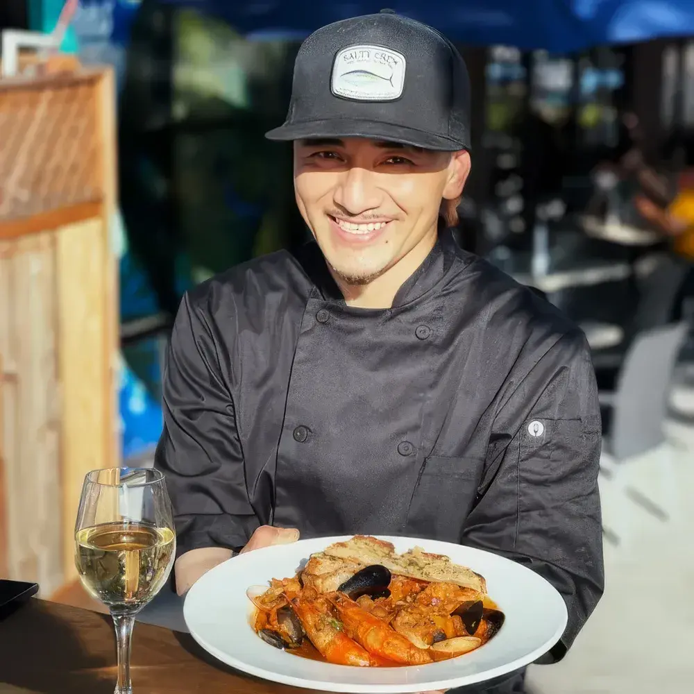 An Umekes chef presenting a plate of seafood on the patio