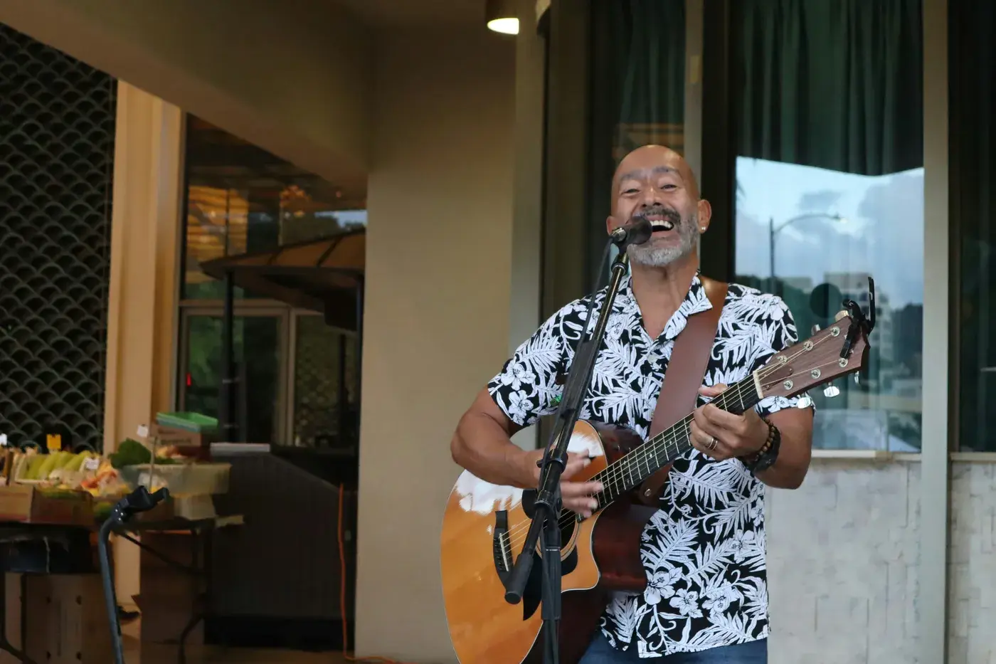 A musician singing with an acoustic guitar at an evening show
