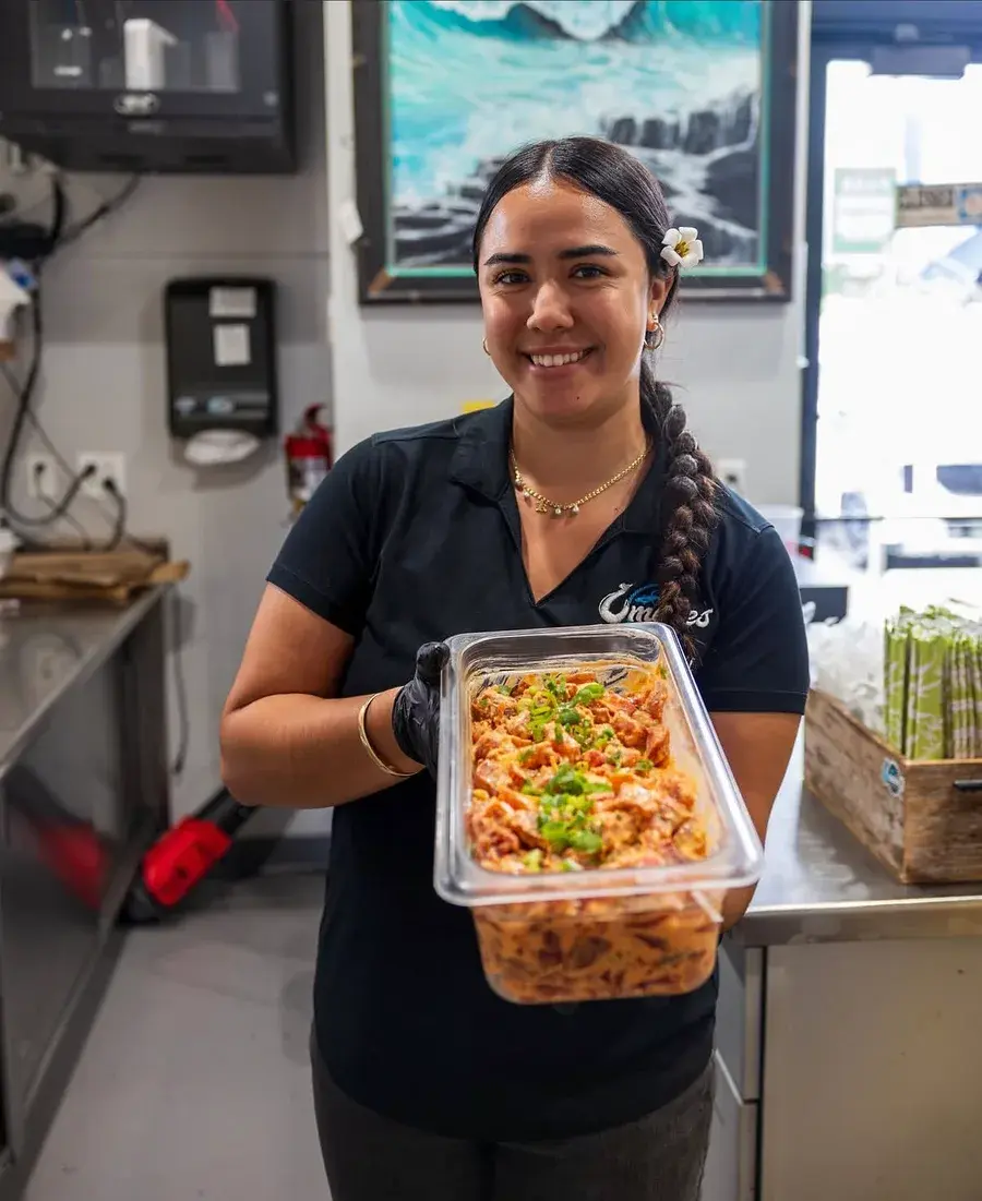 An Umekes team member holding a full pan of fresh spicy ahi poke