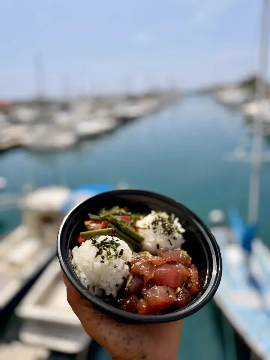 A fresh ahi poke bowl held up at the Honokohau harbor